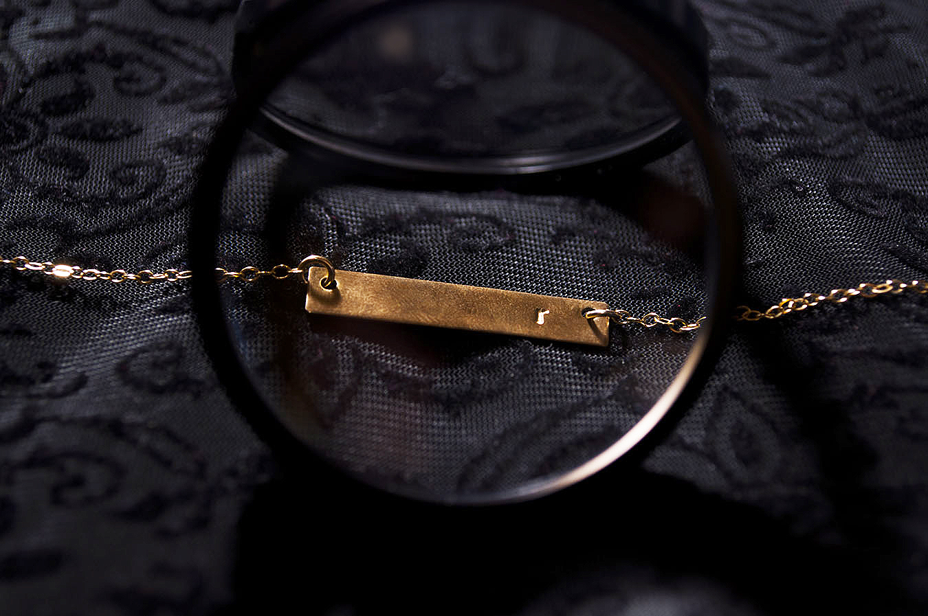 Rebecca_Huang_still_life_photography_dark_velvet_accessories_jewelry_lens_magnifying_reflection_gold_lettered_bar_necklace_chain_floral