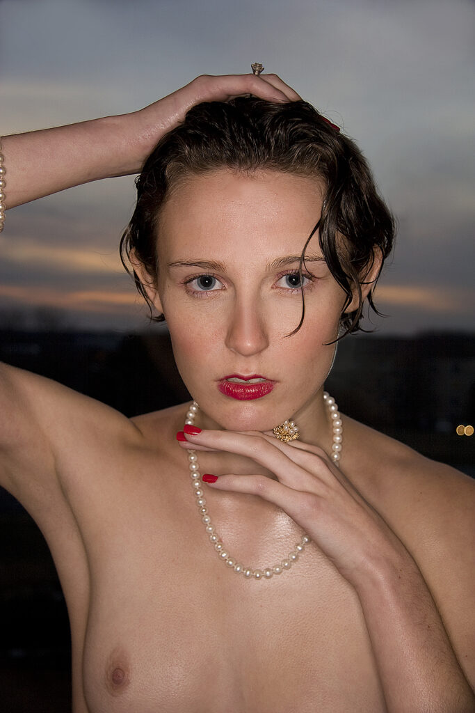 beautiful young woman topless wearing pearls at dusk